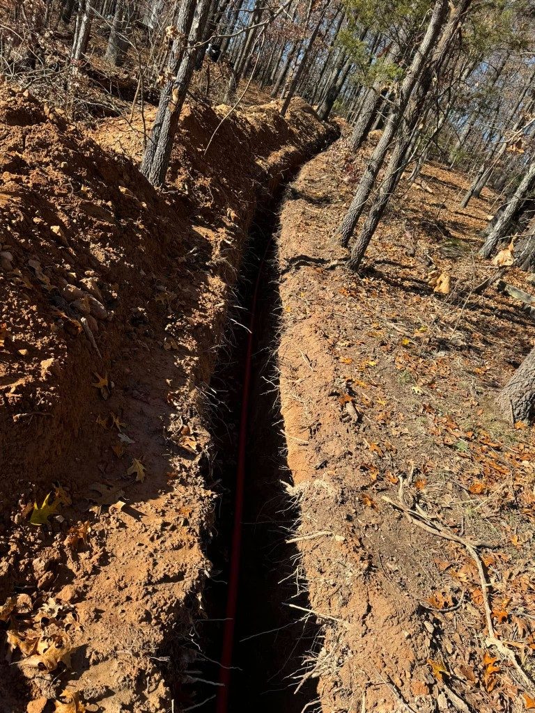 Deep utility trench cut through rocky ground